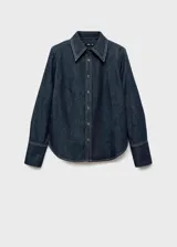 Camisa de denim oscuro con costuras en contraste, cuello camisero clásico, cierre frontal con botones y mangas largas con puños abotonados.