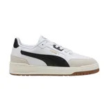 Championes Puma modelo Shuffle Downtown OG, de diseño urbano con base blanca, detalles en negro y suela de goma color caramelo. Presentan refuerzos en gamuza gris en la puntera y el talón, con el logo de la marca en dorado.