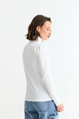 Remera básica de manga larga con cuello polera, confeccionada en tejido suave y elástico.