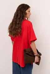 Sobrecamisa roja de lino de manga corta, con cuello solapa, costuras decorativas en contraste y cierre frontal con presillas y botones alargados.
