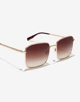Gafas de sol Hawkers unisex modelo Iris, con montura cuadrada dorada de metal y lentes degradadas de marrón a transparente.