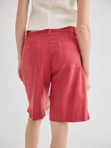 Short de lino color rojo, de tiro medio, con cierre frontal y bolsillos laterales. Presenta un diseño clásico y versátil.