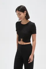 Top de manga corta con textura arrugada, cuello redondo y detalle de frunce frontal con argolla metálica y botón decorativo.