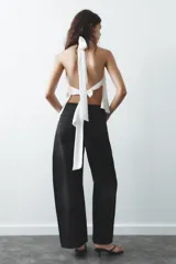 Top blanco de tejido satinado con cuello halter drapeado ajustable con lazada en el cuello y espalda descubierta con lazada.