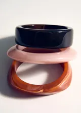 Set de tres pulseras rígidas de resina en tonos rosado, marrón oscuro y carey.