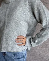 Sweater color crudo de cuello alto con mangas largas y corte holgado.