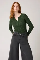 Remera de manga larga verde oscuro con estampado floral en negro, cuello redondo y botones frontales.