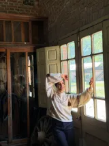 Buzo de punto color crema con diseño oversize, cuello redondo y mangas largas abullonadas. Presenta detalles de costuras decorativas en contraste y apliques de flecos colgantes en la parte frontal y mangas.