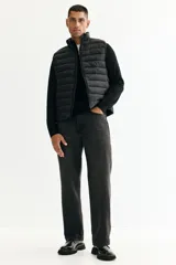Chaleco acolchado de nylon rompevientos, color negro, con diseño guateado, cuello elevado y cierre frontal. Cuenta con bolsillos laterales con cierre y forro interior.