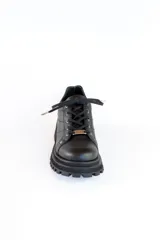 Zapatos de cuero negro con cordones, diseño robusto y suela track dentada. Presentan un detalle metálico en el centro de los cordones.