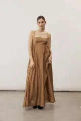 Vestido largo color beige con escote recto, tirantes finos y falda amplia con diseño drapeado.