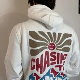 Canguro color caqui con capucha y cordón ajustable. Estampado en la espalda con la frase "The essence of living life fully and energetically", el logo "vibrant journeys", la frase "live for the present" y una cita de Santa Barbara.