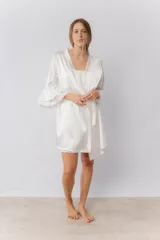 Bata corta de satén elastizado color blanco, con mangas tres cuartos terminadas en volados y lazo ajustable en la cintura.