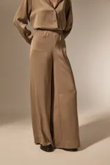 Pantalon de vestir de corte ancho y tiro alto, confeccionado en tela de viscosa con acabado satinado. Presenta cintura elástica y diseño fluido.