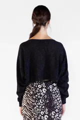 Sweater negro de punto con hilo lurex brillante, escote bote, mangas largas y corte corto tipo crop.