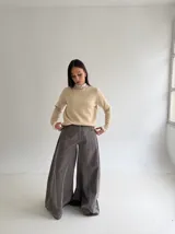 Sweater de punto color beige, con cuello redondo adornado con apliques de pedrería y detalle de puntilla blanca en el cuello y los puños.