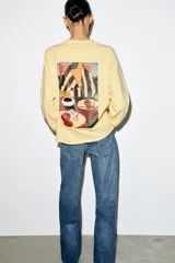 Camiseta de manga larga ranglán y cuello redondo, color amarillo, con estampado frontal a contraste.