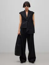 Pantalón negro de corte palazzo, confeccionado en mezcla de lana merino. Presenta cintura alta con cinturilla elástica, bolsillos italianos laterales y bolsillos de vivo en la espalda.