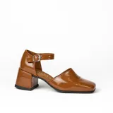 Zapato de cuero vacuno color gris topo, con talón descubierto y pulsera con hebilla. Tiene taco de madera forrado en cuero y suela de goma. La horma es de punta cuadrada, ancha y cómoda.