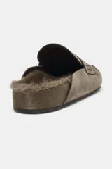 Zueco destalonado tipo mocasín confeccionado en piel, con interior forrado en pelo sintético. Presenta antifaz en el empeine, costuras decorativas y punta redonda.