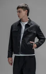 Chaqueta de corte regular crop confeccionada en microfibra pesada levemente elastizada. Presenta un diseño inspirado en la campera de jean clásica, con cuello volcado, cierre frontal mediante broches snap a tono y dos bolsillos delanteros con solapa.