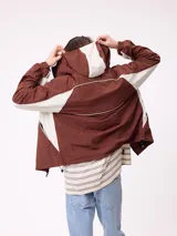 Rompevientos Rusty con capucha, diseño bicolor en azul marino y gris, cierre frontal y logo bordado en el pecho.