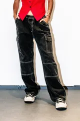 Pantalón jean negro de corte parachute, tiro bajo, pierna ancha y bolsillos cargo.