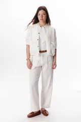 Pantalón de lino color marrón oscuro, tiro alto, corte recto y holgado, con pinzas delanteras y pespuntes a contratono en blanco.