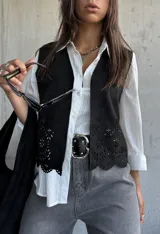 Chaleco negro de gamuza con diseño calado de flores en el ruedo y corte recto.