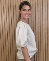 Blusa blanca de lino, con cuello redondo y mangas cortas abullonadas con frunces en los hombros.