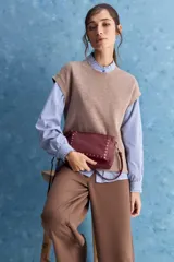 Chaleco de tejido de punto color beige claro, con cuello redondo y diseño de líneas limpias con hombros caídos y terminaciones acanaladas.