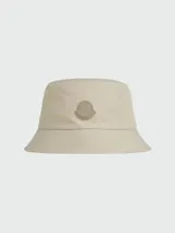 Gorro tipo pescador color beige con logo de la marca Moncler en el frente.