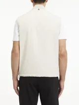 Chaleco blanco hueso acolchado, con cuello alzado de punto de canalé, cierre frontal con cremallera, bolsillos laterales con botón a presión y logo de Calvin Klein en el pecho.