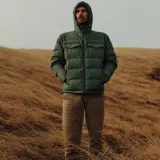 Campera puffer verde oliva con capucha, cierre frontal con cremallera, dos bolsillos de parche con solapa abotonada en el pecho y dos bolsillos laterales con cierre.