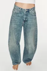 Jeans de tiro medio y corte balloon color azul, con trabillas, bolsillos delanteros y traseros, y cierre frontal con cremallera y botón metálico.