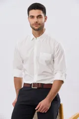 Camisa lisa de manga larga en color blanco, confeccionada en algodón, con cuello camisero, cierre frontal de botones, bolsillo en el pecho y puños ajustables.