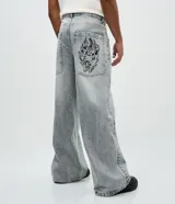 Pantalón de jean color gris claro con efecto desteñido, de corte muy ancho y holgado estilo baggy, tiro medio y bolsillos funcionales.