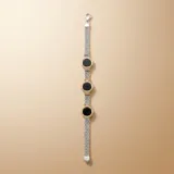 Pulsera de malla tejida en plata, con tres dijes circulares de ónix negro enmarcados en oro amarillo con detalles estriados.