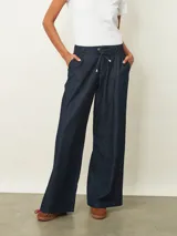 Jean de corte wide leg en color azul oscuro, con cintura elástica ajustable mediante cordón y cierre frontal con botón.