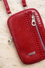 Bandolera porta celular color rojo con textura croco, cierre de cremallera plateada y correa fina ajustable.