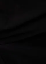 Top negro de diseño asimétrico con escote off-shoulder y detalles drapeados. Es una prenda sin mangas, entallada y confeccionada en tejido fluido.