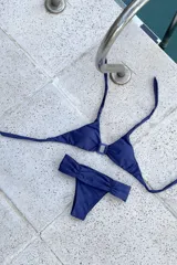 Conjunto de bikini con estampado a cuadros, compuesto por un corpiño triangular con argolla y tiras para atar al cuello y espalda, y una bombacha vedetina ancha con frunces delanteros y traseros.