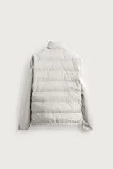 Campera acolchada negra de cuello alto, con cuerpo matelasseado y mangas lisas de tejido elástico. Cuenta con bolsillos en las caderas, cierre frontal por cremallera y bajo con elástico.