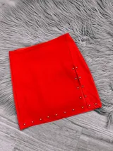 Minifalda roja de bengalina con tajo lateral y tachas plateadas.