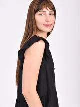 Vestido corto negro con estampado ikat en tonos marrones y beige. Presenta cuello en V con abertura y volados en las mangas cortas. Tiene un corte holgado con un volante en la parte inferior.