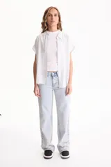 Camisa de viscosa con patrón de rayas verticales en tonos beige y blanco, cuello camisero, manga corta y cierre frontal con botones.