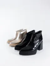 Bota corta negra de cuero charol, con cierre interno, plataforma delantera y taco cuadrado.