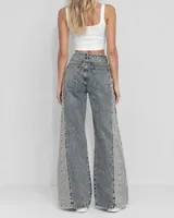 Pantalón jeans de tiro medio, corte wide leg y diseño amplio en las piernas. Presenta un estampado sutil en toda la prenda con franjas laterales de lavado más claro.