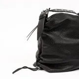 Bolso tipo hobo de cuero negro con textura granulada, cierre superior con cremallera y correa de hombro ajustable con apliques metálicos.