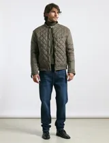 Campera capitoneada de color verde oliva, con cierre frontal de metal y botones a presión. Presenta bolsillos laterales y en el pecho con cierres metálicos, cuello alto y mangas largas.